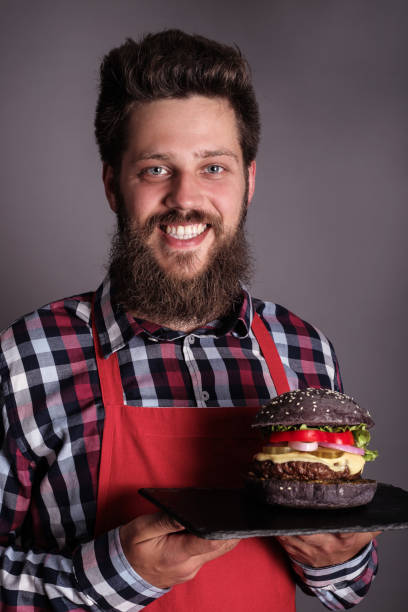mężczyzna kucharz trzymać czarny burger - large cheese beautiful red zdjęcia i obrazy z banku zdjęć