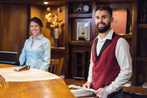 istock Charming hotel employees standing at the reception desk 1198024368