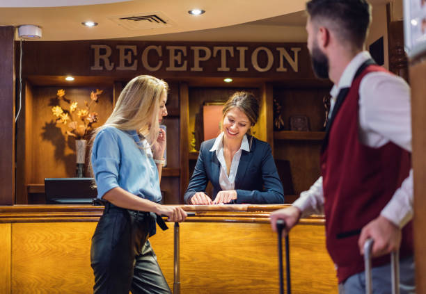 Business woman checking in at the hotel reception desk Confident business woman arriving at the hotel and filling in registration forms door attendant photos stock pictures, royalty-free photos & images