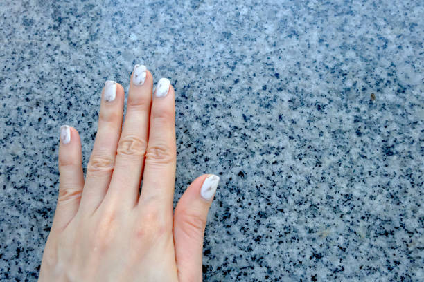 istock White grey manicure nails on granite background texture. Woman hand in gray with modern. Beautiful nail polish design. 1198025866