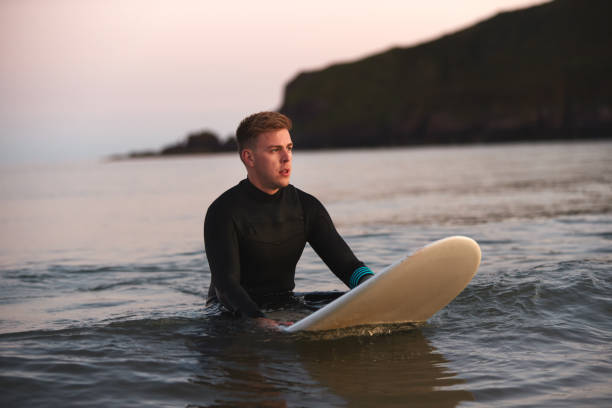 istock Man Wearing Wetsuit Sitting And Floating On Surfboard On Calm  Sea 1198026822
