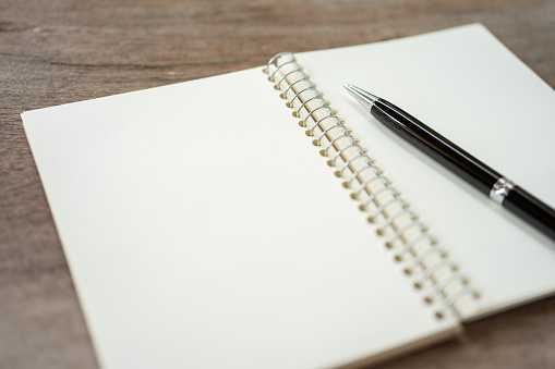 Female hands and note pad with blank paper pages with copy space on white table background.