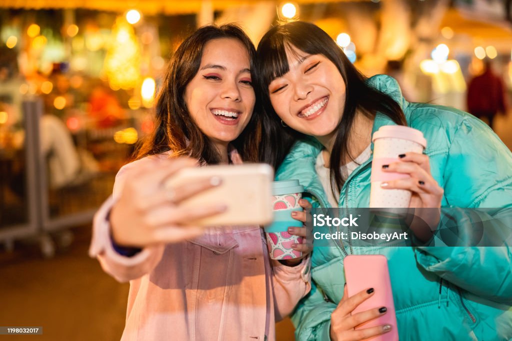 ソーシャルネットワークアプリ用のスマートフォンでビデオを作る幸せなアジアの友人 - 新しい技術トレンドを楽しむ若い女性 - 友情、技術とインフルエンサーのコンセプト - 顔に焦点を当� - 友情のロイヤリティフリーストックフォト