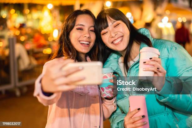 ソーシャルネットワークアプリ用のスマートフォンでビデオを作る幸せなアジアの友人 新しい技術トレンドを楽しむ若い女性 友情技術とインフルエンサーのコンセプト 顔に焦点を当 - 友情のストックフォトや画像を多数ご用意
