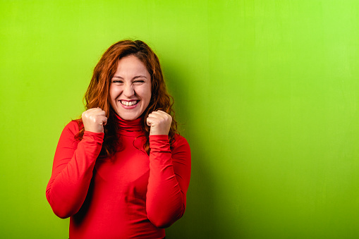 Expressive happy redhead woman on green background and copy space