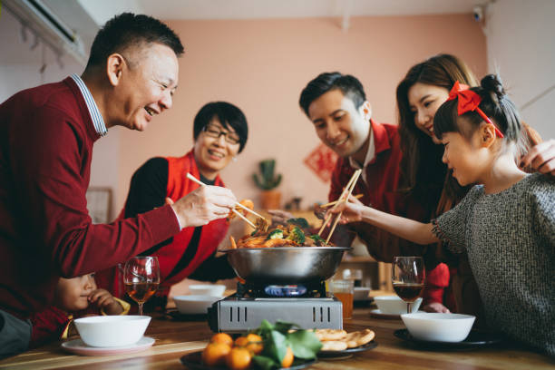 Three generations of joyful Asian family celebrating Chinese New Year and enjoying scrumptious traditional Chinese poon choi on reunion dinner Three generations of joyful Asian family celebrating Chinese New Year and enjoying scrumptious traditional Chinese poon choi on reunion dinner china chinese ethnicity smiling grandparent stock pictures, royalty-free photos & images