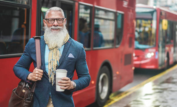 senior business man going to work - hipster przedsiębiorca picia kawy na dworcu autobusowym w londynie - praca, przywództwo, moda i pewna siebie koncepcja - skoncentruj się na twarzy - senior adult outdoors physical activity mode of transport zdjęcia i obrazy z banku zdjęć