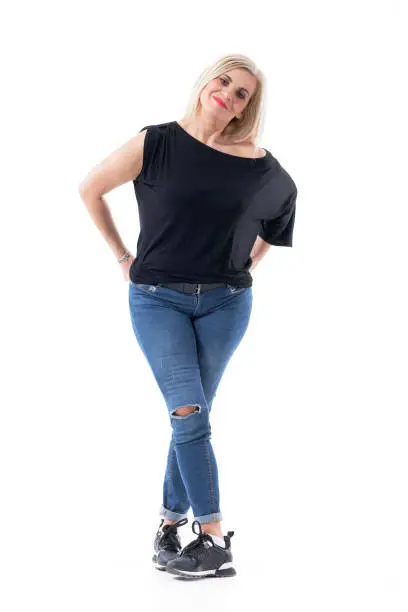 Happy vital modern middle aged blond hair woman posing in casual clothes with arms in back pockets. Full body length isolated on white background.