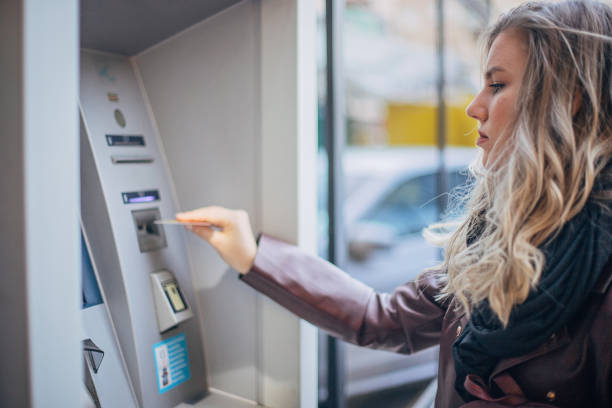 istock Young woman is withdrawing money from ATM machine 1198035392