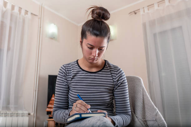 istock A young girl sits next to a laptop and writes notes in a notebook 1198037367