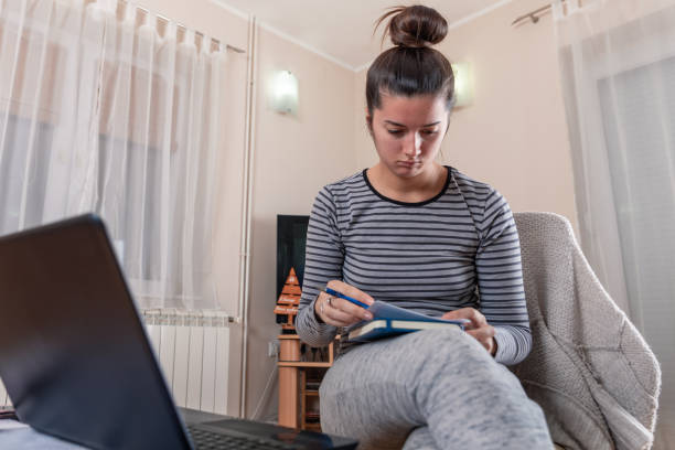 istock A young girl sits next to a laptop and writes notes in a notebook 1198037376