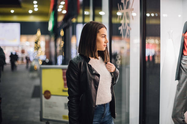 istock Pretty young woman is looking at store window 1198038516