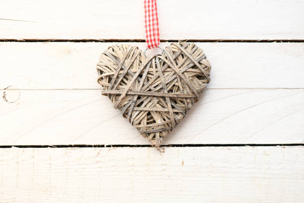 Empty white notebook and pen on the wooden table. Top view, high resolution picture. Empty space in the notebook ready to insert graphics or text.Valentine`s day concept background. Heart on a wooden table.