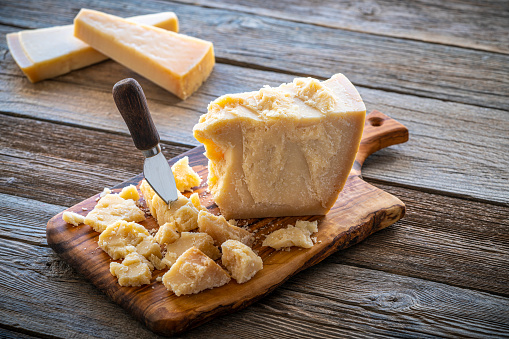 Parmesan Reggiano cheese on cutting board and knife at wooden table