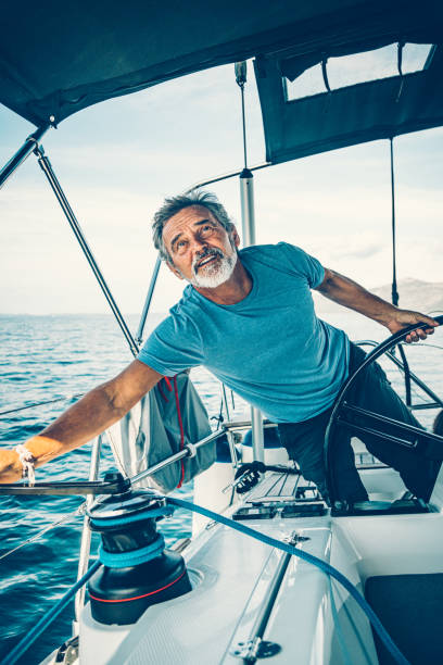 Skipper sailing on sailboat Skipper sailing on sailboat trimming the jib sail with rotating the handle. Taken by Sony a7R II, 42 Mpix. sailboat sports race yachting yacht stock pictures, royalty-free photos & images