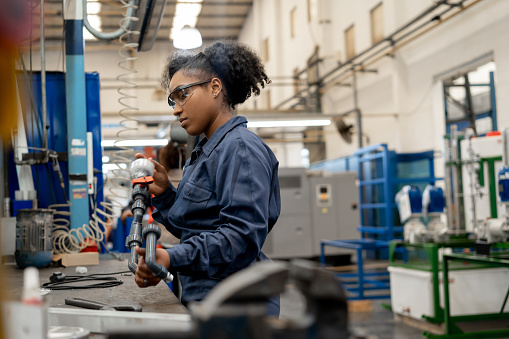 Black woman working on production line of a manufaturing water pump factory - Industrial concepts