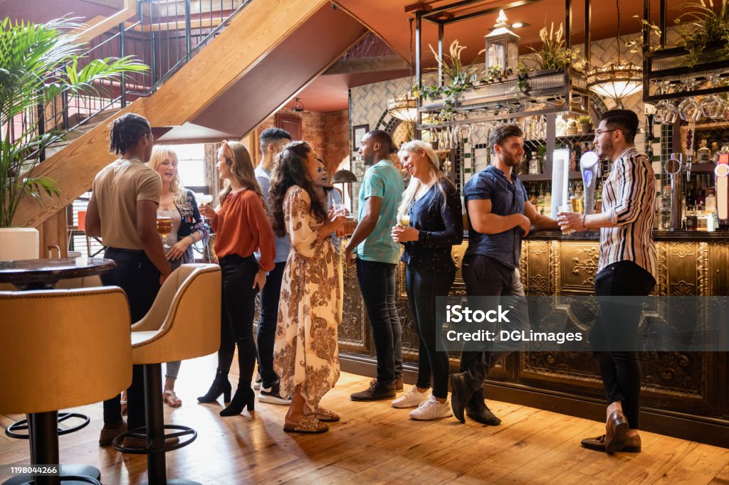 A Drink Before Lunch A wide shot of friends having drinks together at a bar. Bar - Drink Establishment Stock Photo