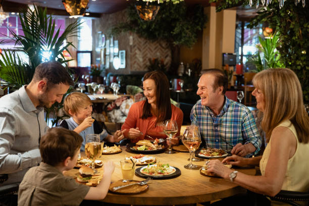 Eating at a Cosy Restaurant A family having a meal at a restaurant. They are laughing with each other. kids restaurant pictures stock pictures, royalty-free photos & images