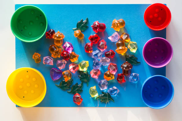 istock Multicolored toy stones scattered on the blue surface and colorful cups for separating by color 1198047714