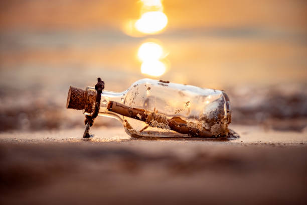 Message in the bottle against the Sun setting down Message in the bottle against the Sun setting down castaway stock pictures, royalty-free photos & images