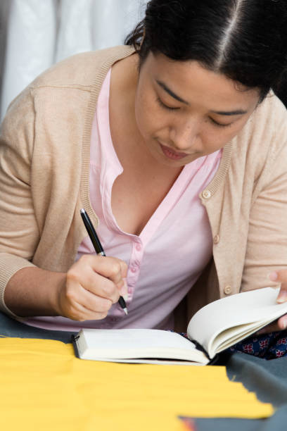 istock asian woman taking notes at seamstress workplace 1198048888