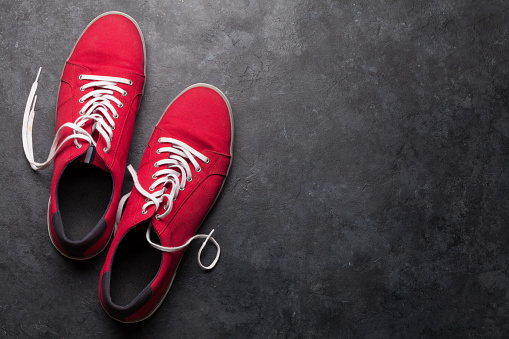 Pair of red sneakers over stone background with space for your text. Top view flat lay