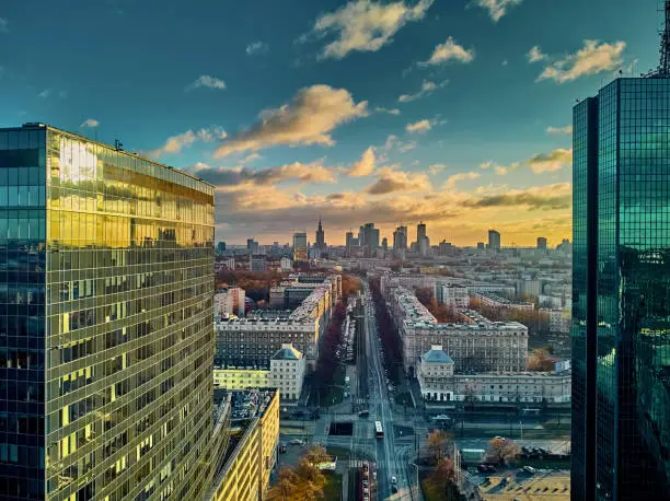 Beautiful panoramic aerial drone view to the enter of modern Warsaw city with silhouettes of skyscrapers in in the rays of the setting winter January sun - amazing sunset, Poland