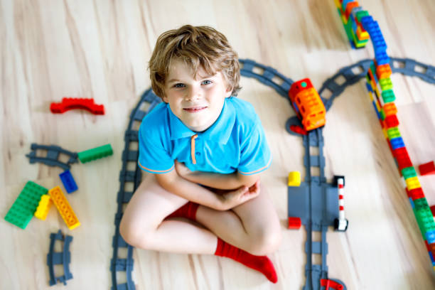 istock little blond kid boy playing with colorful plastic blocks and creating train station 1198057671