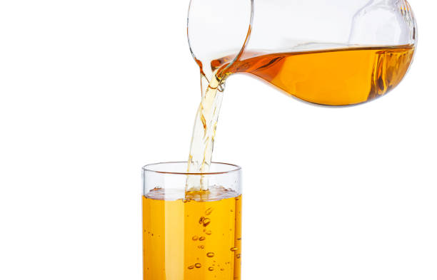 istock Apple juice pouring from pitcher into glass isolated on white background 1198058662