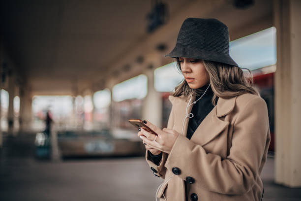 istock Young woman is text messaging while waiting for a train 1198058745