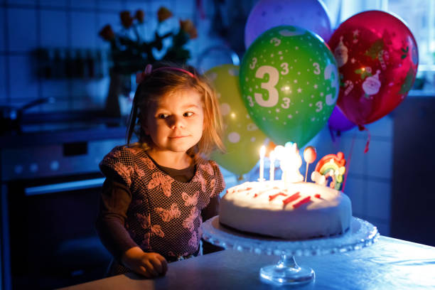 menina adorável da criança pequena que comemora o terceiro aniversário. criança da criança do bebê com bolo caseiro do unicórnio, interno. a criança saudável feliz é surpreendida sobre o sparkler do fogo-de-artifício e velas de sopro no bolo - birthday cake family germany indoors - fotografias e filmes do acervo