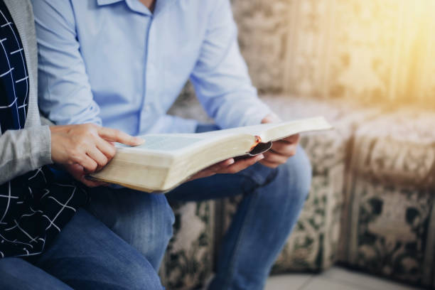 donna mano tenendo e leggere bibbia con i suoi amici al coperto - teologia foto e immagini stock