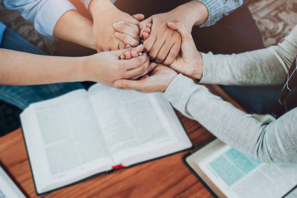 pray together Christian friends joining hand and pray together over bible on wooden table apostle worshipper photos stock pictures, royalty-free photos & images
