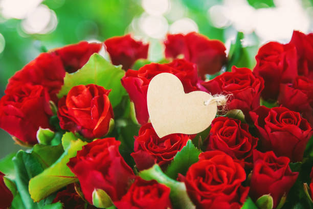 Saint Valentine's wallpaper - wooden heart and bunch of roses surrounded by lights. Romantic / Love background / concept. Valentine's day celebration concept.