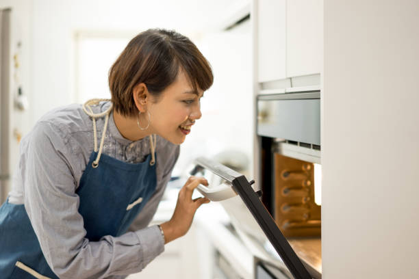 istock Young woman opening oven 1198062254