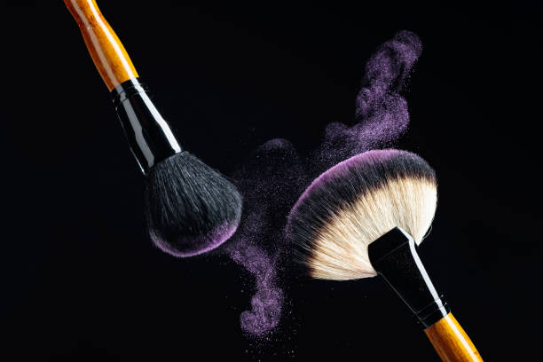istock Makeup concept with a  professional makeup brushes with glowing purple eye shadow isolated on black background. 1198065637