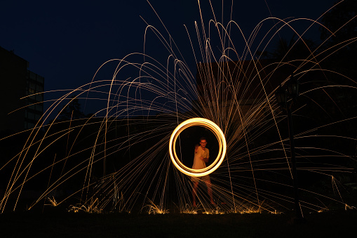 a long exposure photography of an steel wool on fire going in circles and dropping iron on fire as a shower