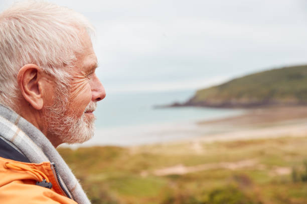 istock Profile Shot Of Active Senior Man Walking Along Coastal Path In Winter With Beach And Cliffs Behind 1198067914