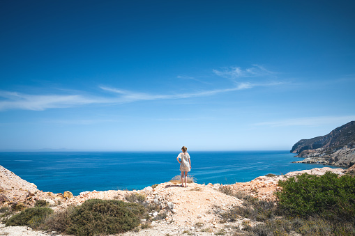 Young woman enjoying the view from the cliff of Milos island (Cyclades, Greece).