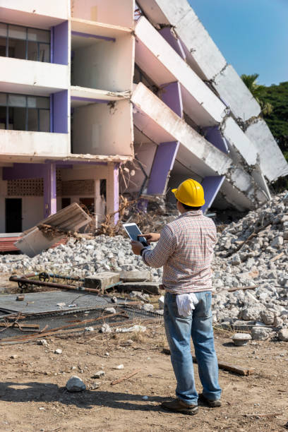 Engineer holding tablet is checking for destruction, demolishing building. stock photo