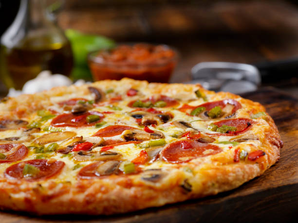 pizza deluxe con pepperoni, salchicha, champiñones y pimientos - pizza fotografías e imágenes de stock