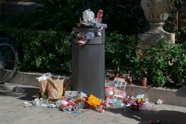 Valencia, Spain - 16th March, 2019: Full trash can with empty drinks packages and food wrappers on the street.