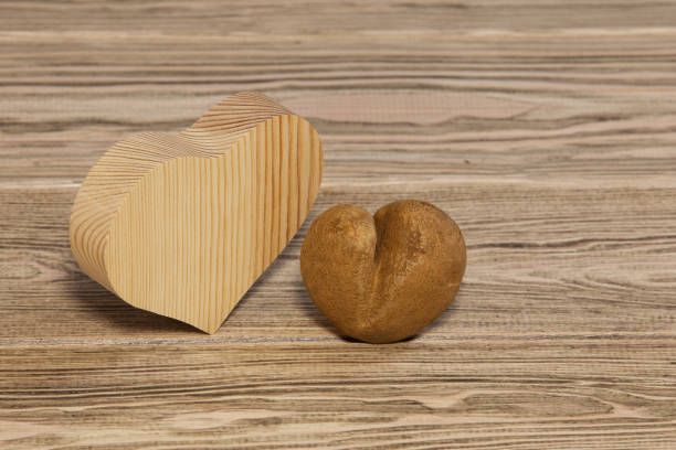 木製の背景に面白い醜いジャガイモ。 - heart shape raw potato food individuality ストックフォトと画像