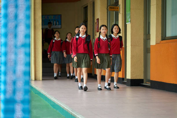 istock Female students walking in corridor at school 1198081470