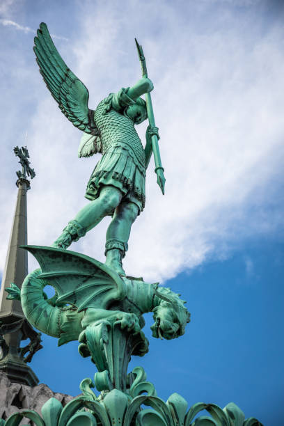 Close-up on Archangel Saint Michael statue on the roofs of Basilica Notre Dame de Fourviere majestic monument in French city of Lyon Archangel Saint Michael (St Michel in french) statue close-up, on the roofs of Basilica Notre Dame de Fourviere built between 1872 and 1884, in a dominant position overlooking the city of Lyon, and dedicated to the Virgin Mary. This image was taken during a sunny summer day in famous Lyon city in Rhone department, Auvergne-Rhone-Alpes region in France (Europe), outside Basilica Notre Dame de Fourviere, on Fourviere hill. fourviere stock pictures, royalty-free photos & images