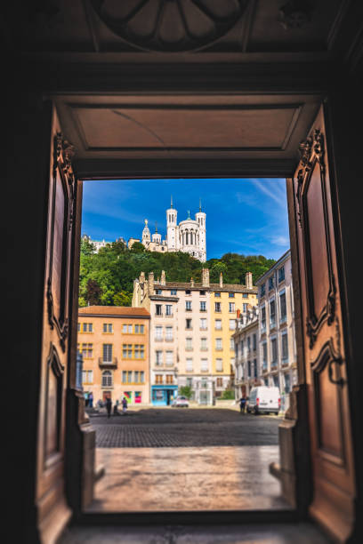 Basilica Notre Dame de Fourviere tilt-shift view from the entrance doors of Saint Jean-Baptiste cathedral in Vieux Lyon French city Basilica Notre Dame de Fourviere with tilt-shift lens focus effect view from the entrance opened doors of Saint Jean-Baptiste cathedral in Vieux Lyon, at the foot of Fourviere hill. The Basilica was built between 1872 and 1884 Romanesque and Byzantine architecture, in a dominant position overlooking the city of Lyon, and dedicated to the Virgin Mary. This image was taken during a sunny summer day in famous Lyon city in Rhone department, Auvergne-Rhone-Alpes region in France (Europe). fourviere stock pictures, royalty-free photos & images