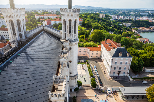 High angle view of famous french Fourviere hill from the slate roofs of the Basilica Notre Dame de Fourviere monument built between 1872 and 1884, in a dominant position overlooking the city of Lyon, and dedicated to the Virgin Mary. This image was taken during a sunny summer day in famous Lyon city in Rhone department, Auvergne-Rhone-Alpes region in France (Europe), outside Basilica Notre Dame de Fourviere.