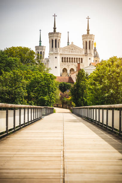 Basilica Notre Dame de Fourviere in Lyon city French monument viewed from the footbridge of the four winds empty pedestrian walkway in summer Majestic Basilica Notre Dame de Fourviere French monument viewed from the footbridge of the four winds (in french : passerelle des Quatre-Vents) empty pedestrian walkway. The Basilica was built between 1872 and 1884, in a dominant position overlooking the city of Lyon, and dedicated to the Virgin Mary. This image was taken during a sunny summer day in famous Lyon city in Rhone department, Auvergne-Rhone-Alpes region in France (Europe), outside Basilica Notre Dame de Fourviere, on Fourviere hill. fourviere stock pictures, royalty-free photos & images