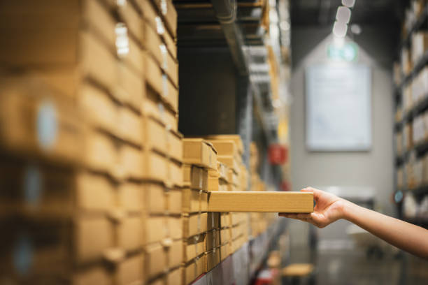 cardboard box package with blur hand of asian shopper woman picking product from shelf in warehouse. customer shopping lifestyle in department store or purchasing factory good concepts. - department store imagens e fotografias de stock