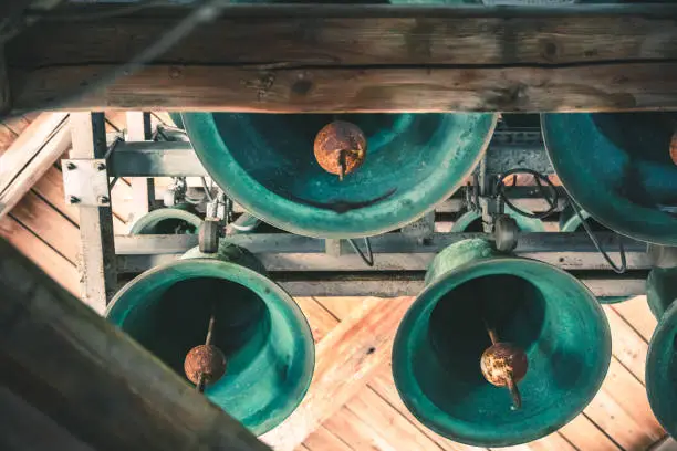 Details on the large and very old bells hanging on wooden beams from the steeple of Basilica Notre Dame de Fourviere, in one of the bell tower. They are still in use and active. The Basilica was built between 1872 and 1884 with Byzantine and Romanesque architecture style, in a dominant position overlooking the city of Lyon, and dedicated to the Virgin Mary. It features fine mosaics and superb stained glass very ornate with gold and some paintings on the ceiling. This image was taken inside this famous place of worship monument in Lyon city, in Rhone department, Auvergne-Rhone-Alpes region in France (Europe), on Fourviere hill.